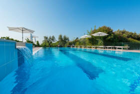 Das Schwimmbad ist von Weinreben umgeben und bietet ein großzügiges Solarium mit Liegestühle und Sonnenschirmen an mit Blick zum See